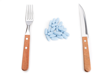 Concept preparation to eating pills with a knife and fork. On a white .の写真素材
