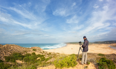 Male photographer traveling and photography in the dunes. With tripod and Camera.