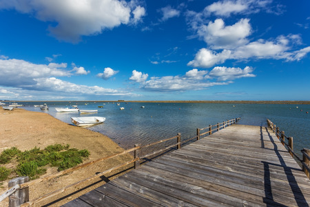 Old wooden bridge on the bay and the boats on the water. の写真素材