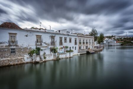 A dramatic urban landscape of ancient houses on the river. Tavira, Portugal.の写真素材