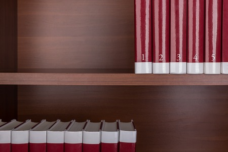 Old encyclopedias on a wooden shelf. Close up.の写真素材