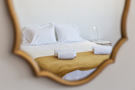 Reflection in the mirror of a bed with pillows, in the bedroom.の写真素材