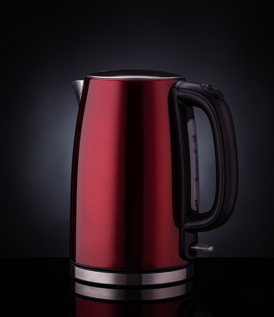 Red modern electric kettle on a black background.の写真素材