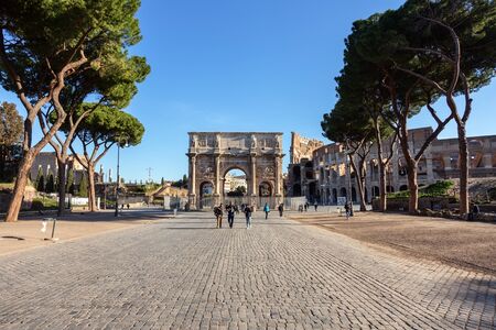 Rome Italy, March 20, 2019 Tourists walk along an alley in front of the Constanin Arch.