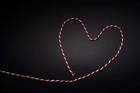Conceptual image of a rope on a black background, in the shape of a heartの写真素材