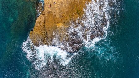 Waves of turquoise water washed by the rocky stone coast of Portugal. Aerial view.