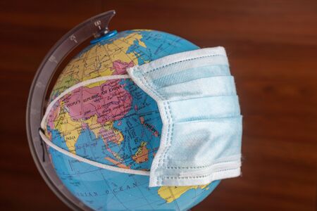 The concept of the globe is covered with a protective mask against coronavirus covid 19 infection.の写真素材
