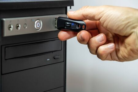 Hand inserting a USB flash drive into a computer.の写真素材