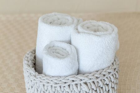 Rolled soft towels in basket on white background. Ð¡lose up.