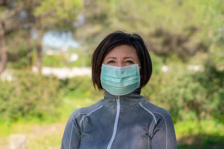 Woman athlete in the park put on a protective mask from coronavirus and allergies.の写真素材