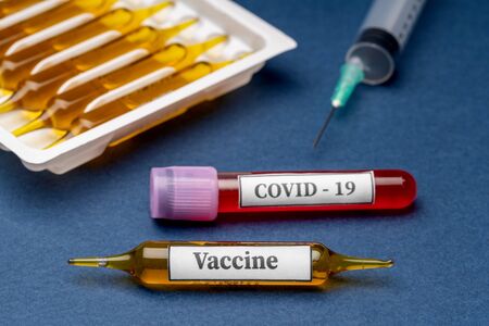 Medical capsules in the box from coronavirus virus and an injection and test tube on the table on a blue background.の写真素材