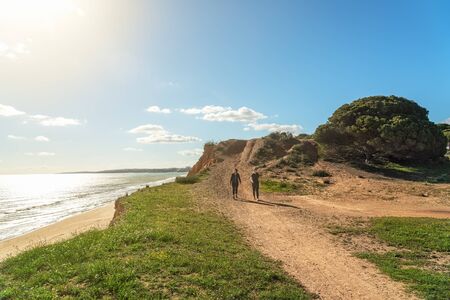 Two girls athletes in sports uniforms, walk along the cliff shore, in the summer near the sea. Beach...