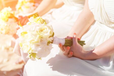 Bridesmaids at the wedding, on a sunny day, with a beautiful bouquet of flowers in their hands.の写真素材