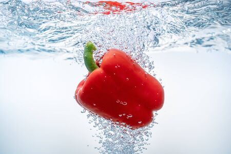 Falling red bell peppers in ecological clear water. Close-up.の写真素材