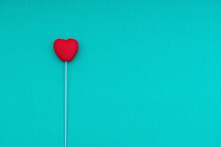 Red heart on a stick, on a pink background. Conceptual and creative photography. Copy space.の写真素材