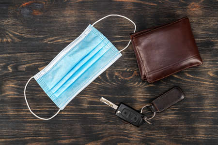 Top view of medical mask, keys and wallet placed on a table. Essential items during covid19 epidemic. High quality photoの写真素材