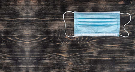 Top view of face mask or surgical mask lays on wooden table with copy space. COVID-19 diseases prevention and allergies concept. High quality photoの写真素材