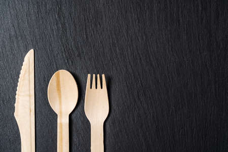 Disposable biodegradable tableware made of wood spoon, knife and fork on marble texture. Close-up. High quality photoの写真素材