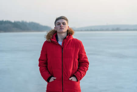 A young guy teenager, in a red jacket, poses and reflects emotionally about life, against the...