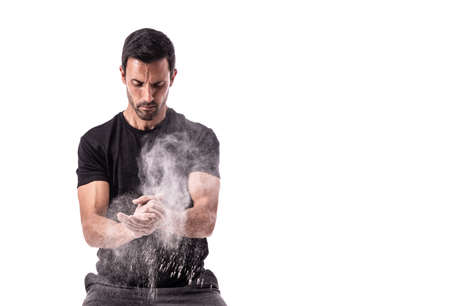 European athlete preparing for training, clapping his hands, with chalk, raising a cloud. On a white isolated background. High quality photoの写真素材