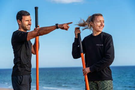 A middle-aged man the trainer and a woman in a fitness class on the seashore. Ocean, sand and blue...