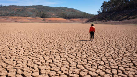 Silhouette of a man on a sandy cracked empty not fertile land during a drought. The concept of ecological catastrophe on the planet. High quality photoの写真素材