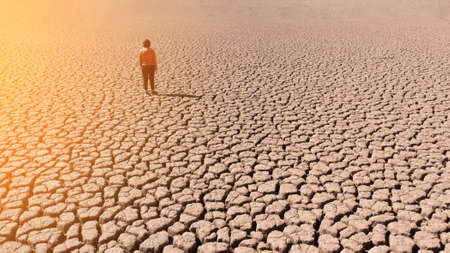 Silhouette of a man on a sandy cracked empty not fertile land during a drought. The concept of ecological catastrophe on the planet. High quality photoの写真素材
