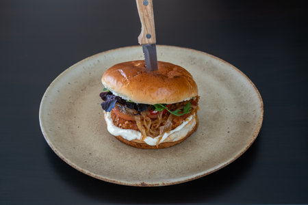 Hamburger burger cheeseburger with pork chicken cheese on a plate and a stuck knife.