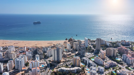 Aerial view of Portuguese city of Portimao with high-rise buildings on the coast with beaches. Tourist cruise liner in background in sea.の写真素材