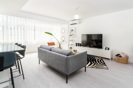 Modern apartment living room interior with gray sofa and TV area and plaid basket.