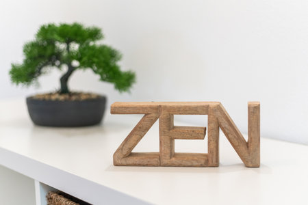 A wooden sign spelling ZEN sits on a shelf beside a small bonsai tree, creating a calming atmosphere in a modern indoor spaceの写真素材
