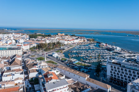 Visitors enjoy the lively dock area in Faro, Algarve, where boats are moored. The old town offers views over Ria Formosa and surrounding buildingsの写真素材