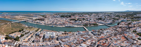 Tavira in Algarve is seen from above, featuring the river and white buildings with a clear sky. The view captures the towns layout and surrounding landscape. Panorama River Gilao and Roman bridgeの写真素材