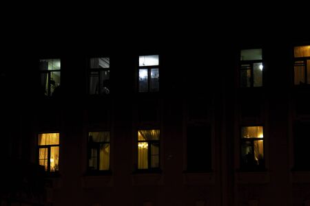 Glowing apartment windows at night where each occupant has his own privacyの写真素材
