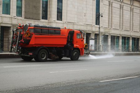 orange truck loaded with water barrels watering a roadwayの写真素材