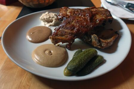 cooked pork ribs with spices and cucumbers on a plate in a cafe