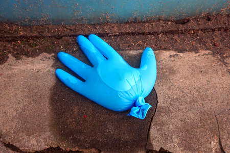 blue latex medical glove filled with water lying on the pavementの写真素材