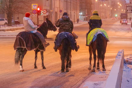 February 20, 2021, Russia, St. Petersburg, Three riders on horseback at an intersection await a green traffic light during a morning blizzardのeditorial素材
