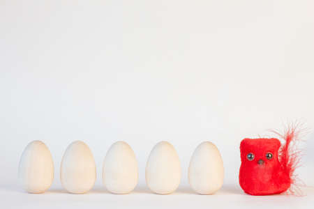 Easter decoration: red chicken and five wooden eggs on a light background with place for textの写真素材
