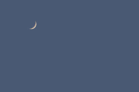 Background image: moon in the new moon phase high in the evening blue skyの写真素材