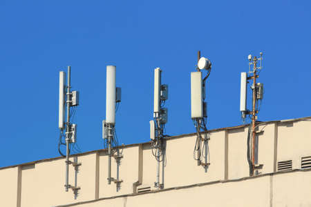 cellular antennas on the roof of a building against the blue sky