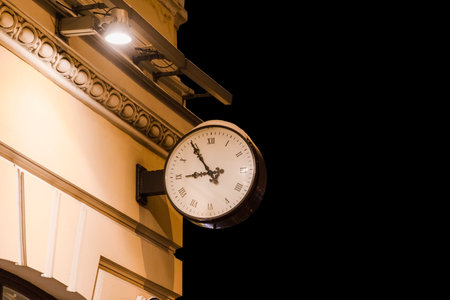 a street clock on the wall of a building covered in snow showing five minutes to nineの写真素材
