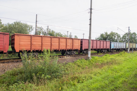 a train of multi-colored freight gondola cars traveling along a railway