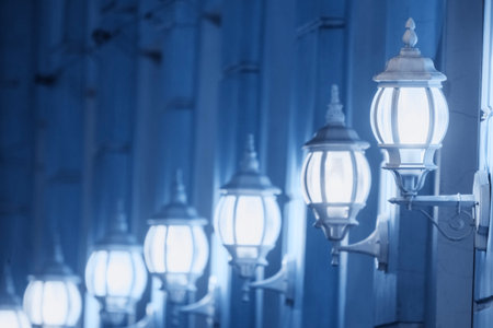Retro lanterns on the facade of the building illuminating the wall with cold white lightの写真素材