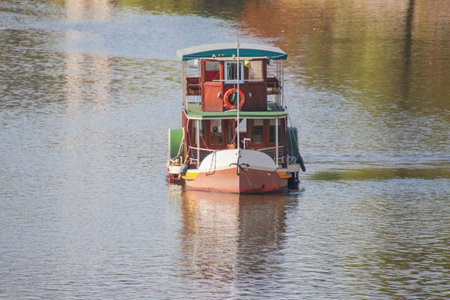 A pleasure boat floating on a river, reflected in the water