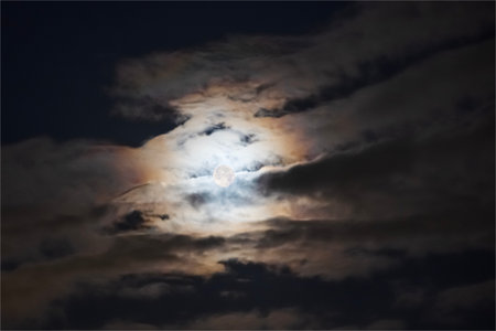 a full moon high in the night sky, illuminating the cloudsの写真素材