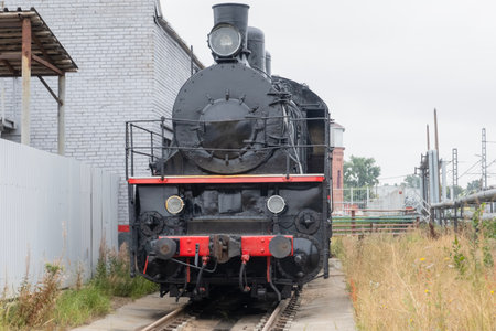 A steam locomotive on a siding next to a gray fenceの写真素材