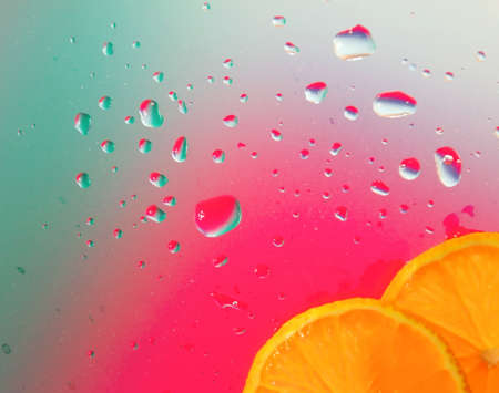 Abstract background. Sections of the orange (mandarin) on glass with water drops