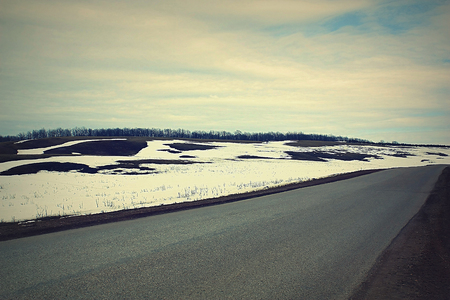 Spring countryside road and land with snowの写真素材