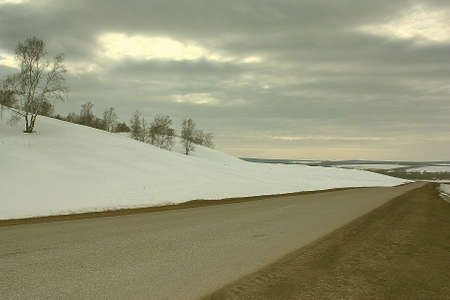 Spring countryside road and land with snowの写真素材